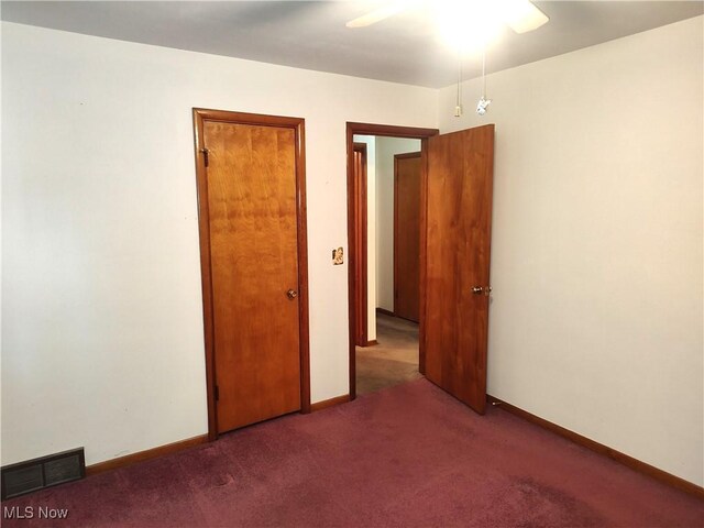 unfurnished bedroom with ceiling fan and dark colored carpet