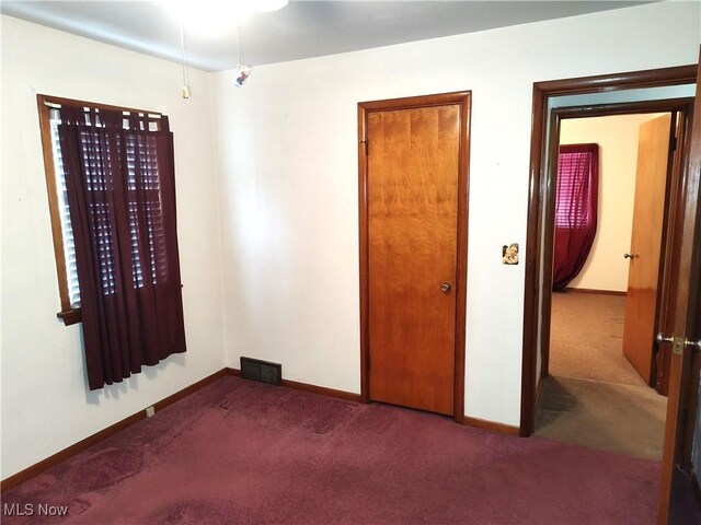 unfurnished bedroom with dark carpet