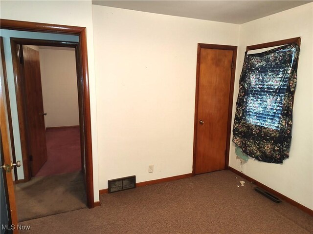 unfurnished room featuring dark colored carpet