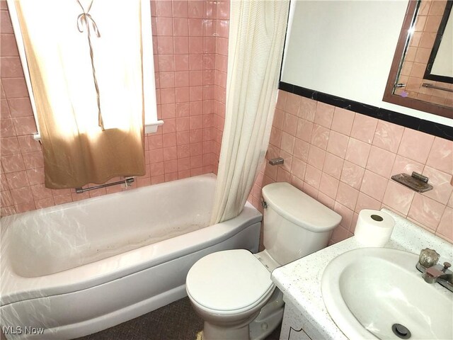 full bathroom with vanity, toilet, shower / tub combo, and tile walls