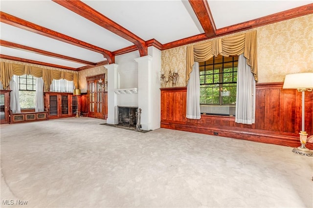 unfurnished living room featuring beamed ceiling, decorative columns, carpet, and a wealth of natural light