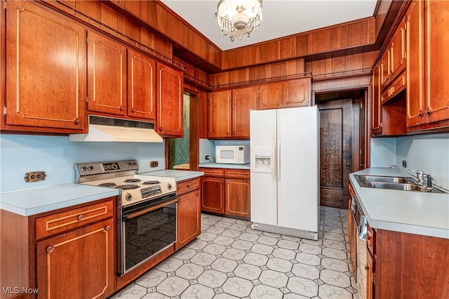 kitchen with white appliances, sink, and a notable chandelier