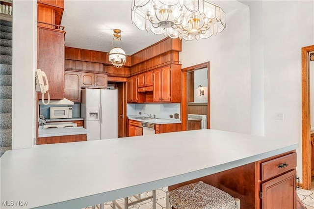 kitchen featuring a notable chandelier, white appliances, decorative light fixtures, and kitchen peninsula