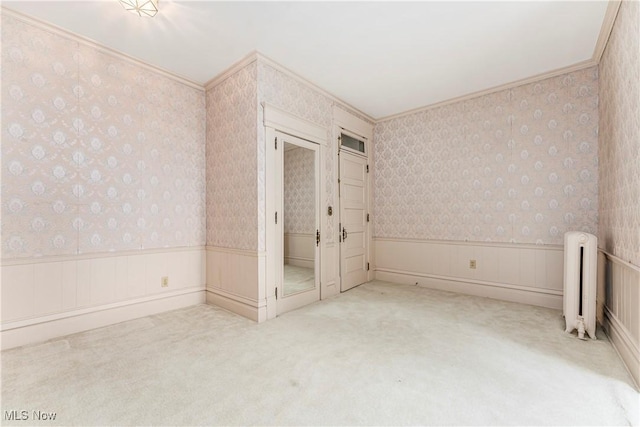 unfurnished bedroom with crown molding, light colored carpet, and radiator