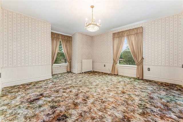 spare room with an inviting chandelier, radiator heating unit, and carpet