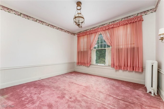 carpeted empty room with crown molding, radiator heating unit, and a chandelier