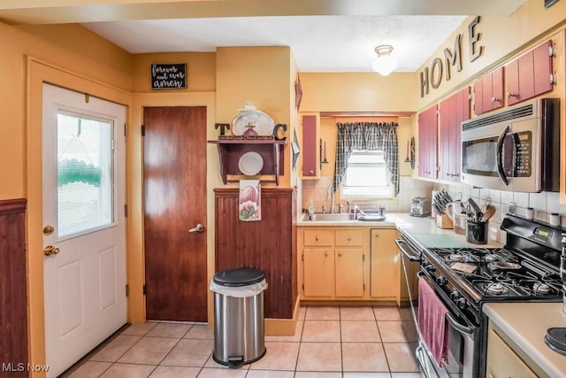 kitchen featuring sink, gas stove, decorative backsplash, and light tile patterned floors