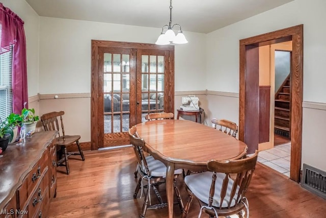 dining area featuring french doors, a healthy amount of sunlight, a chandelier, and light hardwood / wood-style floors