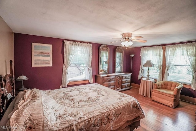 bedroom featuring ceiling fan, light hardwood / wood-style floors, and a textured ceiling