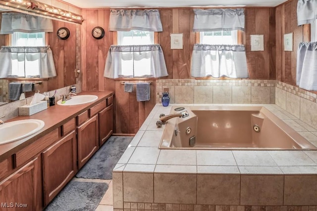 bathroom with a relaxing tiled tub, vanity, and wooden walls