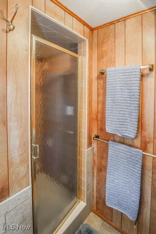 bathroom featuring a shower with door, a textured ceiling, and wood walls