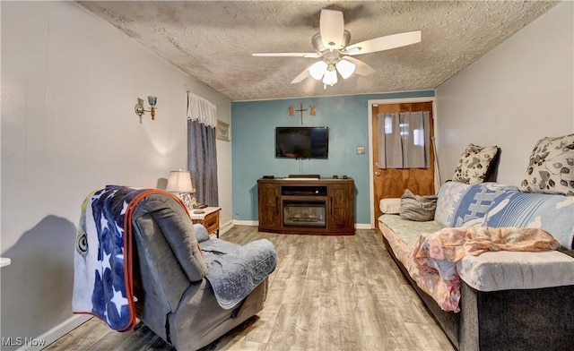 living room featuring ceiling fan, hardwood / wood-style flooring, and a textured ceiling