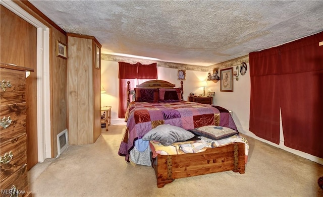 bedroom with light colored carpet, a textured ceiling, and wood walls