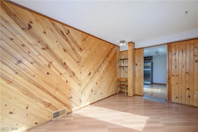 spare room with hardwood / wood-style flooring and wood walls