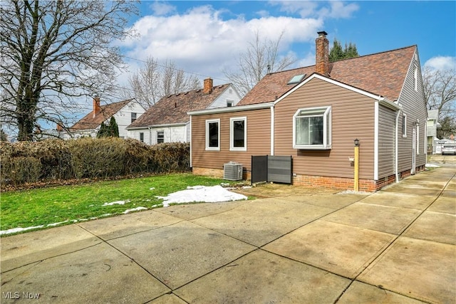 rear view of property with central AC unit and a yard