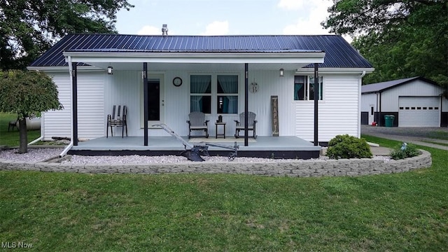 view of front of property with a garage, an outdoor structure, a front yard, and covered porch