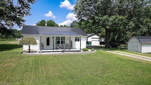 rear view of house with a porch, a garage, a yard, and a storage unit