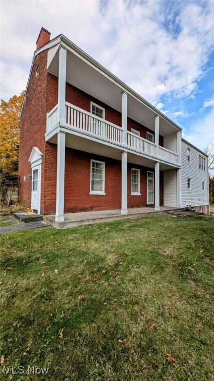 rear view of house with a balcony and a yard