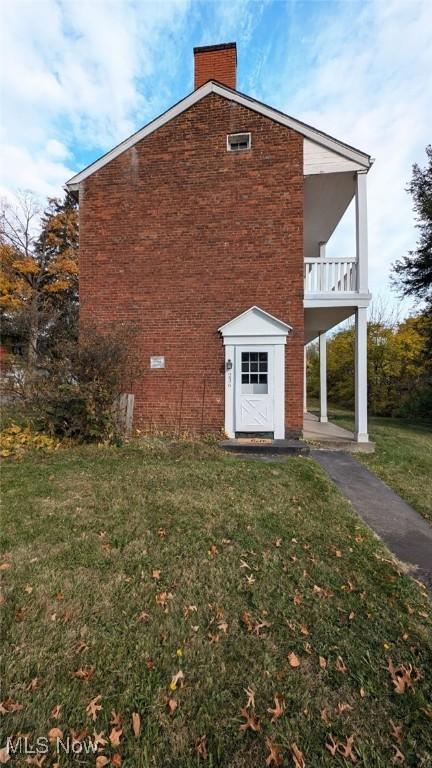 view of property exterior featuring a balcony and a yard