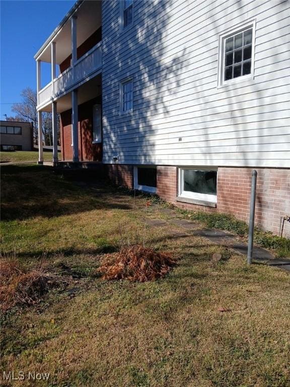 view of side of property featuring a yard and a balcony