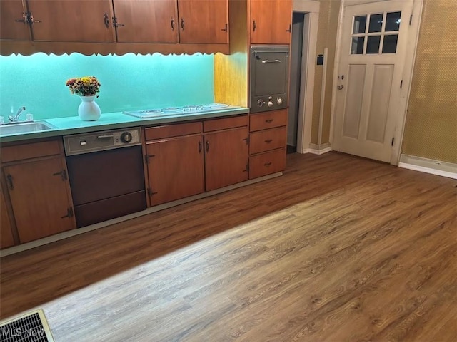 kitchen with cooktop, dark hardwood / wood-style floors, dishwasher, and sink