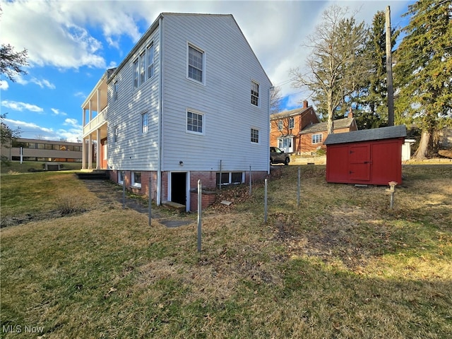 rear view of house featuring a balcony, a yard, and a storage unit