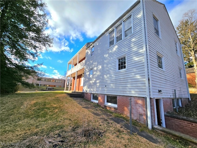 view of side of home featuring a balcony and a lawn