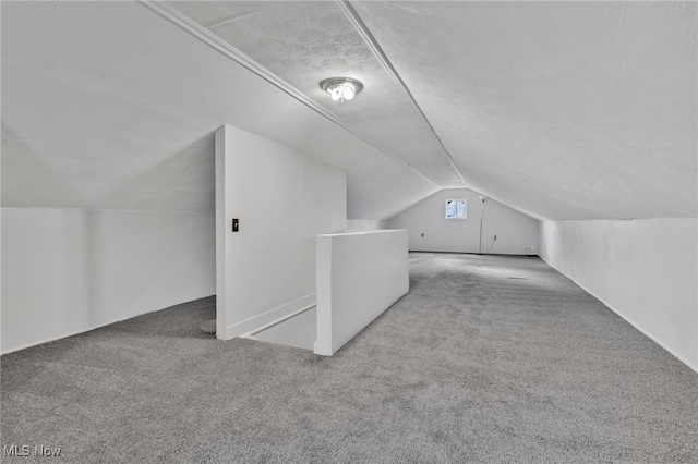 bonus room with light carpet, vaulted ceiling, and a textured ceiling