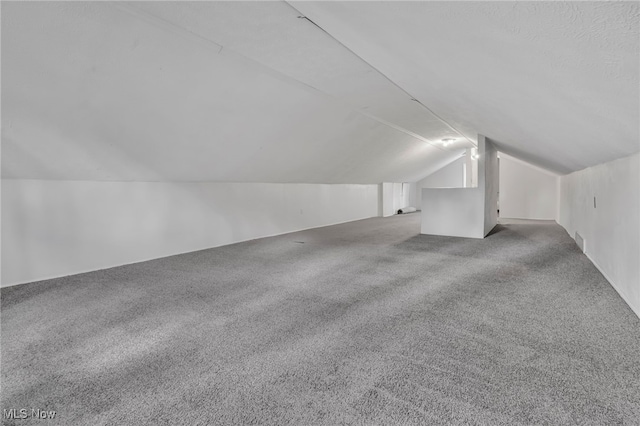 bonus room with vaulted ceiling and carpet floors