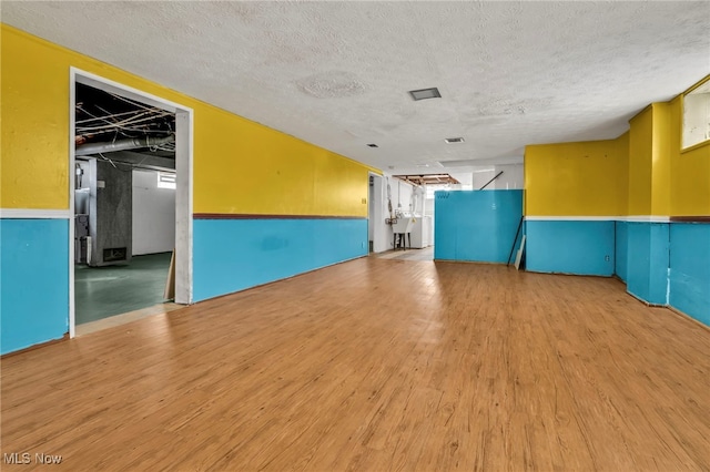 spare room featuring a textured ceiling and light hardwood / wood-style flooring