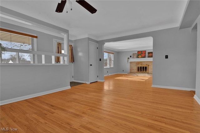 unfurnished living room with ceiling fan, light hardwood / wood-style floors, and a brick fireplace