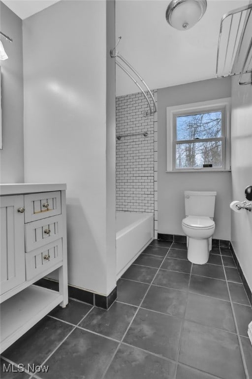 bathroom featuring toilet, tiled shower / bath combo, and tile patterned flooring