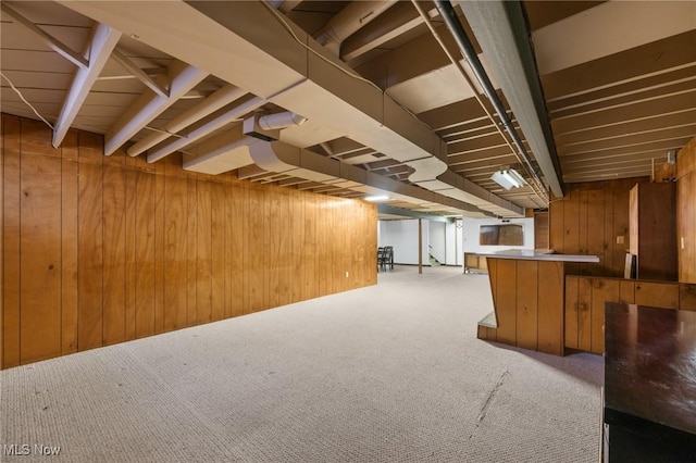 basement featuring light colored carpet and wood walls