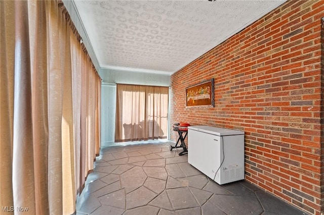 hall with brick wall and a textured ceiling