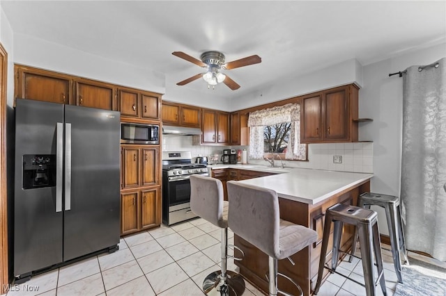 kitchen featuring appliances with stainless steel finishes, a kitchen breakfast bar, kitchen peninsula, and decorative backsplash