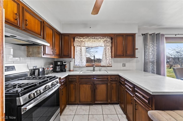 kitchen featuring sink, ceiling fan, stainless steel gas stove, tasteful backsplash, and kitchen peninsula