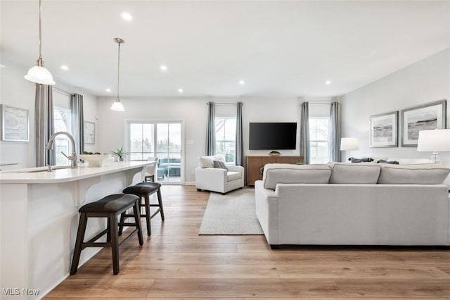 living room featuring a healthy amount of sunlight, sink, and light wood-type flooring