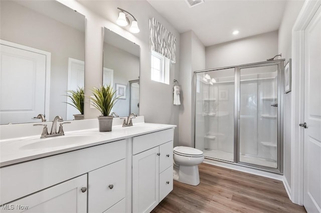 bathroom with an enclosed shower, hardwood / wood-style floors, vanity, and toilet