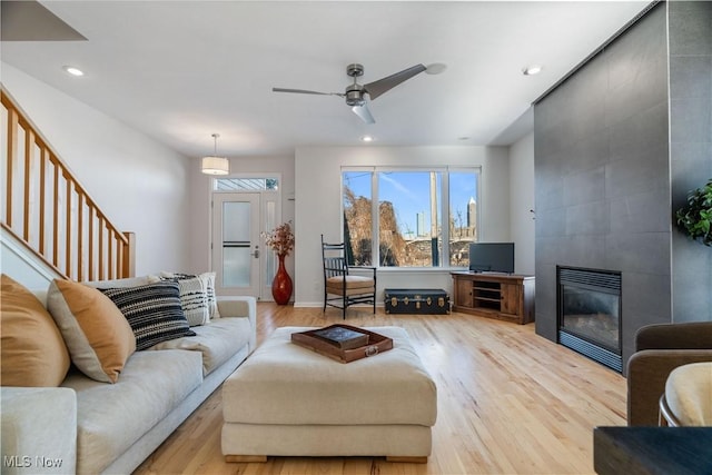 living room with ceiling fan, a fireplace, and light wood-type flooring