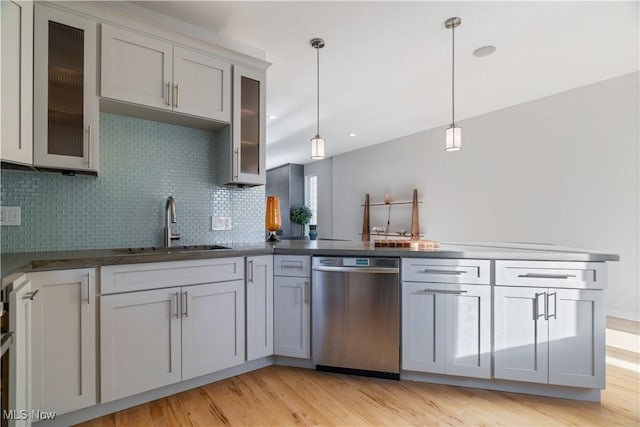 kitchen featuring pendant lighting, sink, decorative backsplash, stainless steel dishwasher, and light wood-type flooring