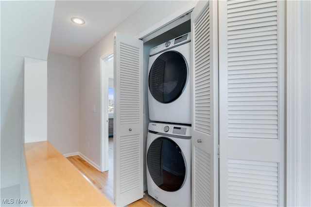 washroom with stacked washer and dryer and light hardwood / wood-style floors