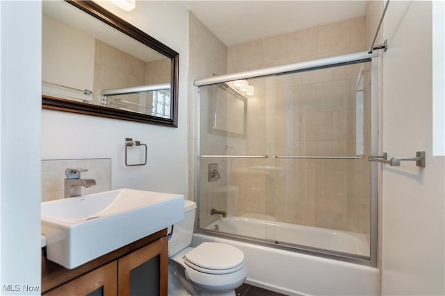 full bathroom featuring vanity, combined bath / shower with glass door, and toilet