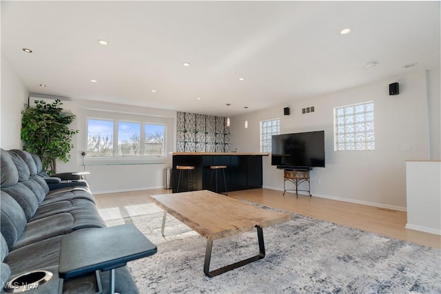 living room with a healthy amount of sunlight, bar area, and light hardwood / wood-style flooring