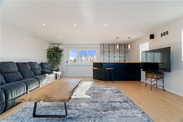 living room with a healthy amount of sunlight, bar area, and light hardwood / wood-style flooring