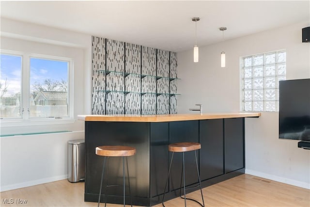 bar with pendant lighting, light hardwood / wood-style floors, and a wealth of natural light