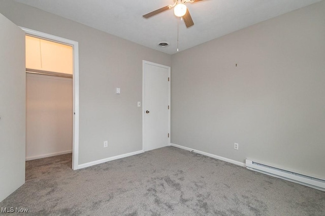 unfurnished bedroom with a baseboard radiator, a walk in closet, carpet, ceiling fan, and a closet