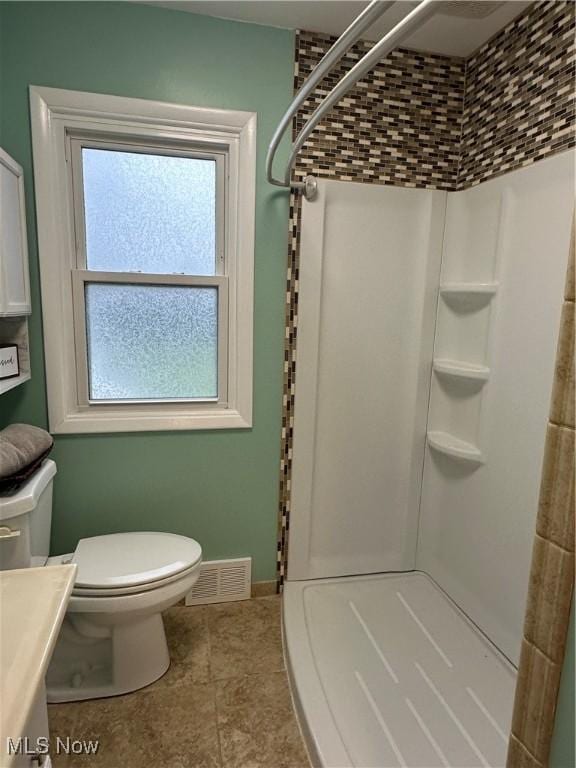 bathroom featuring toilet, vanity, and walk in shower