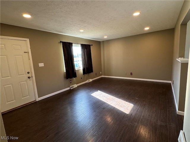 empty room with dark wood-type flooring and a textured ceiling