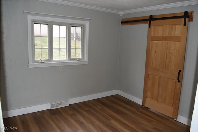 empty room with crown molding, a barn door, and dark wood-type flooring