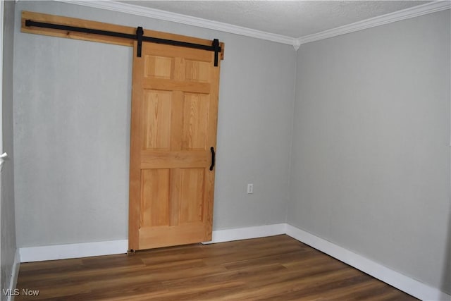 unfurnished room with dark wood-type flooring, a barn door, a textured ceiling, and crown molding